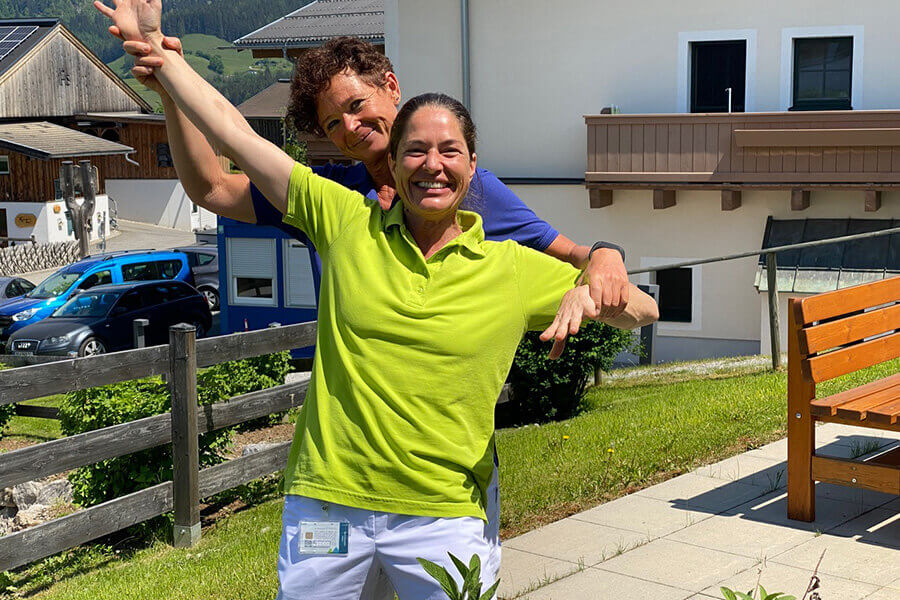 Zwei Physiotherapeutinnen im Freien, die zusammen Übungen zur Bewegungsentwicklung durchführen.