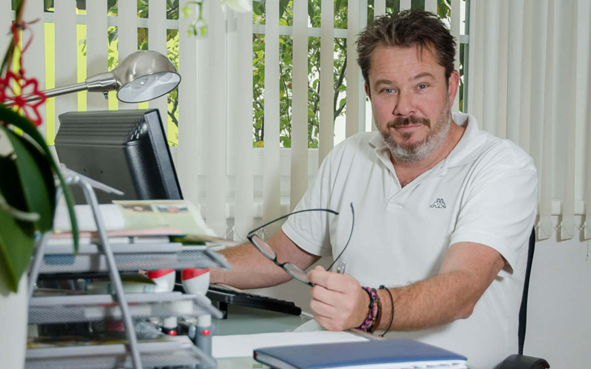 Dr. Bernhard Kinger sitzt am Schreibtisch in der Privatklinik Ritzensee und betrachtet seine Brille.