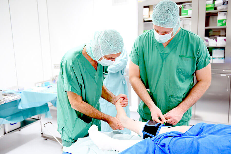Ärzte in OP-Kleidung behandeln das Bein eines Patienten in einer modernen Klinik.