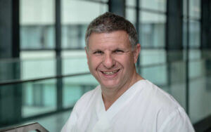 Dr. med. Peter Schatzl in der Privatklinik Ritzensee, lächelnd in moderner Umgebung.