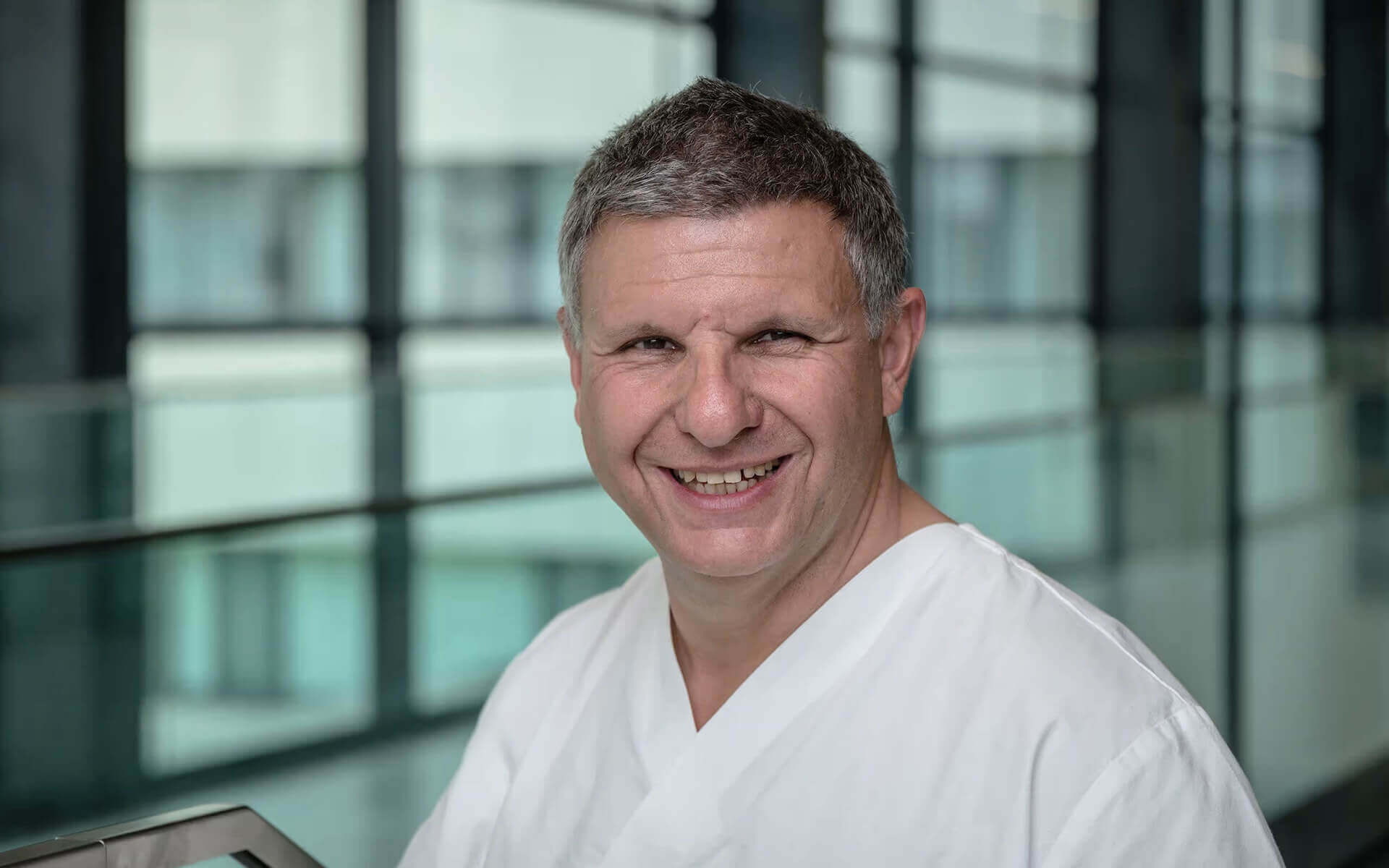 Dr. med. Peter Schatzl in der Privatklinik Ritzensee, lächelnd in moderner Umgebung.