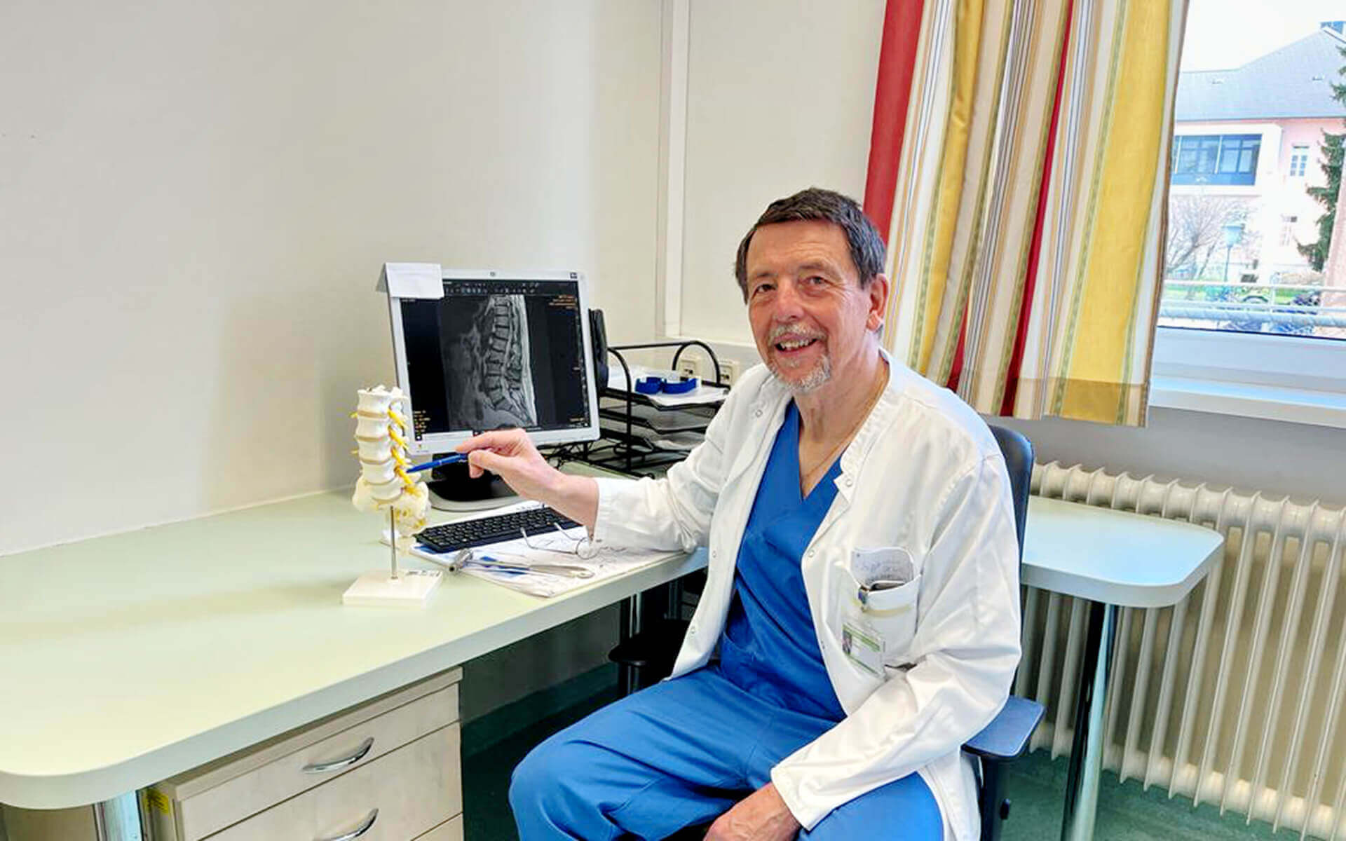 Arzt mit Wirbelsäulenmodell in einer modernen Sprechstunde der Privatklinik Ritzensee.