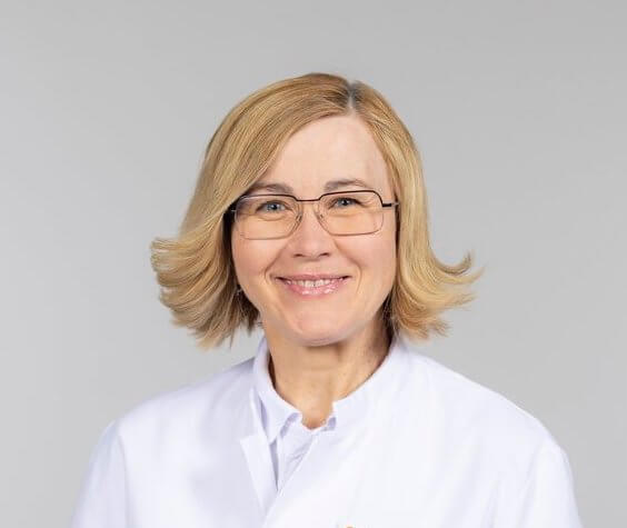 Dr. Maryna Wüstner lächelnd in weißem Kittel, erfahrene Ärztin in der Privatklinik Ritzensee.
