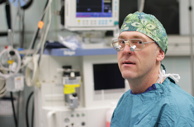 Arzt in Sterilkleidung und Operationsmaske in moderner Klinikumgebung.